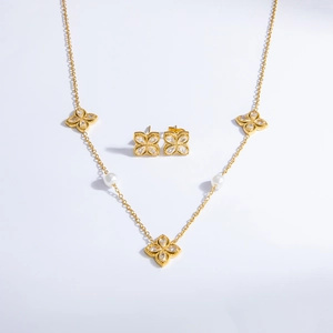 Detailed close-up of 18k gold clover jewelry set with crystals and white pearls