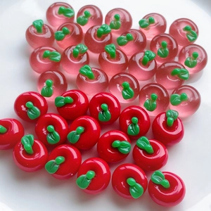 Close-up of small 3D resin apples in translucent pink and solid red for DIY crafts