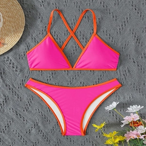 Flat lay of pink and orange contrast halter bikini with beach hat and flowers