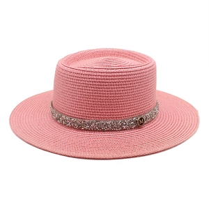 Close-up of pink boater hat with rhinestone band and metallic M logo detail