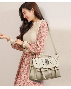Detail of off-white rock style crossbody bag with skull ornament and metal studs