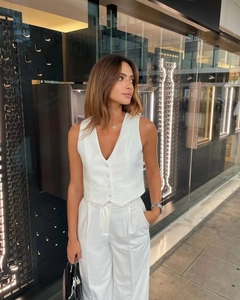 Détail d'un ensemble gilet blanc à col en V et d'un pantalon large à taille haute