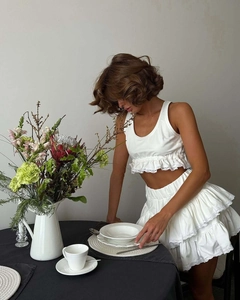 Detailed view of white two-piece set featuring lace trim and ruffled tiered cake skirt