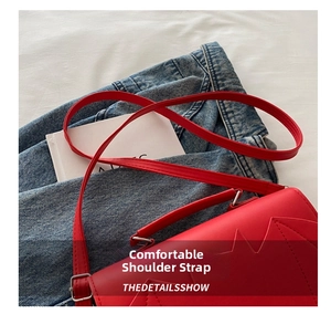 Detail of red crossbody bag showing adjustable leather shoulder strap and silver buckle