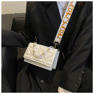 Close-up of white quilted crossbody bag with golden chain and wide patterned strap