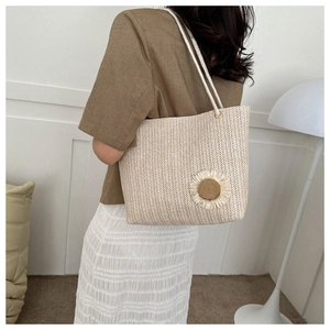 Detail of a beige woven tote bag with a sunflower accent styled for a beach holiday