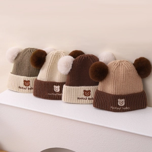 Details von vier erdfarbenen Strickmützen für Babys mit Pompons und Bärenstickerei