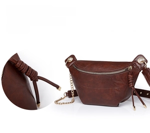 Detail der braunen Leder-Gürteltasche mit Goldkette und glattem Reißverschluss-Quast