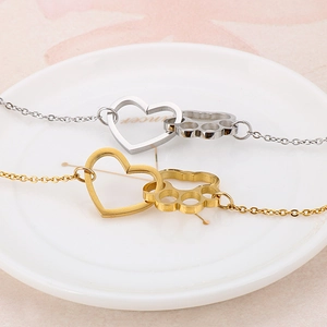 Gold and silver heart paw print stainless steel bracelets on a white ceramic plate