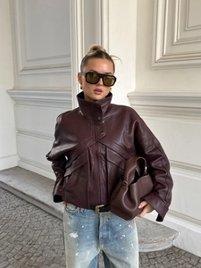 Détail de la veste en similicuir marron foncé grainé dans un décor de rue élégant