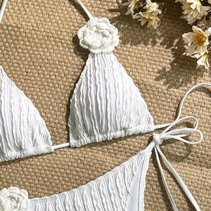 Detailed close-up of white textured bikini set with delicate 3D crochet floral accents