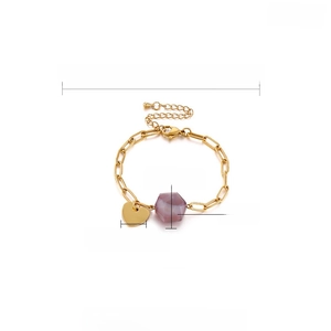 Detail of adjustable gold stainless steel bracelet with purple stone and heart charm