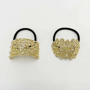 Detail of two gold metal hair ties with pearl and rhinestone geometric ornaments