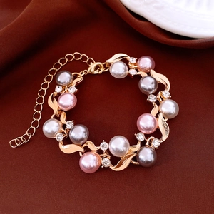 Detail of gold chain bracelet with white pink grey pearls and sparkling rhinestones