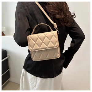 Détail du motif matelassé à losanges et de la poignée de ce sac à bandoulière beige