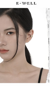Detail view of a two-tone silver ear cuff with red accents worn by a model in profile