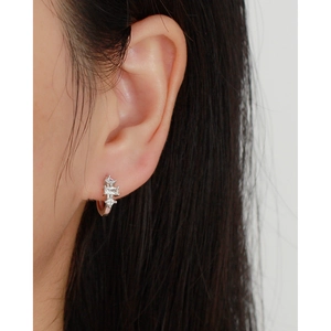 Close-up of geometric s925 silver hoop earrings with clear zircons on a model's ear