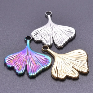 Macro detail of ginkgo leaf pendants in gold, silver, and iridescent stainless steel