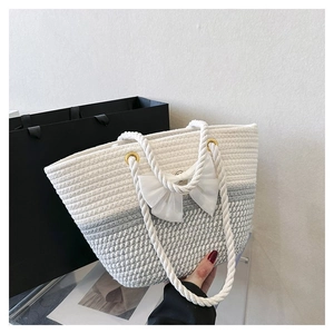 Close-up of a woven cotton rope tote bag with a white bow on a marble surface