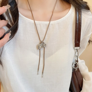 Close-up of heart-shaped zircon pendants on a brown cord necklace worn by a model