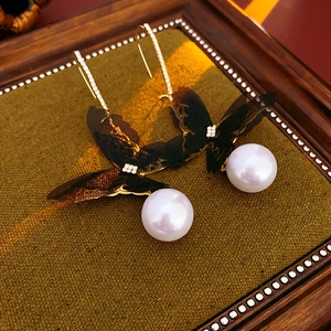 Detail of butterfly wing earrings with sparkling rhinestones and white pearls
