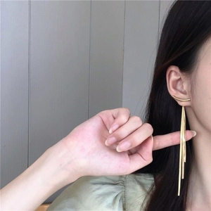 Elegant gold long tassel earrings shown on a model with minimalist metal design