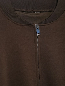 Close-up of brown knit jacket featuring ribbed collar and silver metallic zipper detail