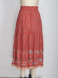 Détail d'une jupe longue évasée rouge à motif floral présentée sur un mannequin