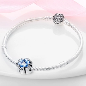 Detalle de pulsera de plata con girasol y colgante de esmalte azul con circonitas cúbiche claras