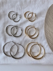 Flat lay of minimalist gold and silver hoop earrings in three sizes on white fabric