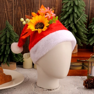 Classic red plush Christmas hat with sunflower and floral decor on wooden background