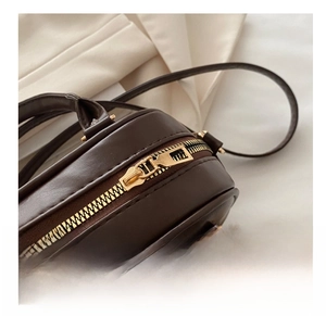 Macro detail of the smooth golden metal zipper closure on the vintage brown pillow bag