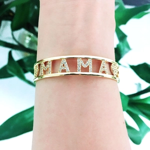 Close-up of gold chain bracelet featuring MAMA lettering with sparkling crystal stones