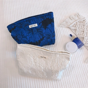 Macro shot of blue floral embossed jacquard cosmetic bag with silver zipper detail