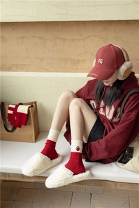 Close-up of red cashmere socks with owl embroidery and white plush slippers for winter