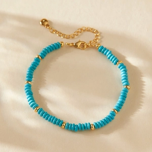 Detail eines blauen Perlenarmbands mit goldenen Zwischenstücken und Karabinerverschluss