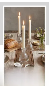 Vertical ribbed clear glass skirt candle holder on a rustic wooden dining table