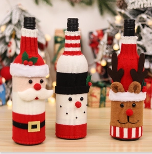 Close-up of knitted Santa, snowman, and elk wine bottle covers on a festive table