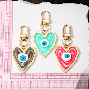 Three colorful resin heart evil eye keychains in green, brown and red with gold hooks