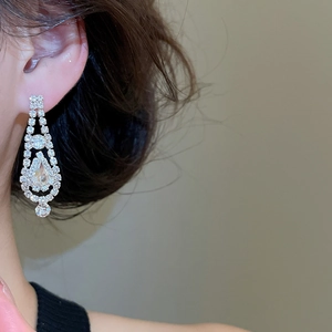 Close-up detail of silver diamond teardrop tassel earrings worn by a female model