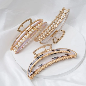 Three acetate hair claws with gold metal frame in pink and white marble patterns