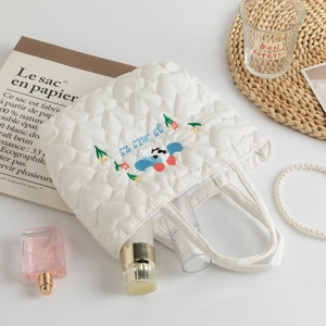 Detail of white heart-quilted handbag with cute dog embroidery and cosmetics storage