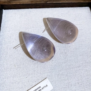 Close-up of minimalist translucent acrylic teardrop stud earrings with cat-eye texture