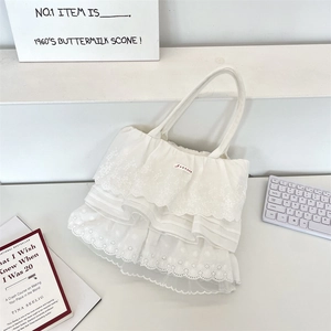 Dettaglio di balze in pizzo bianco e ricamo floreale sulla borsa tote in tela