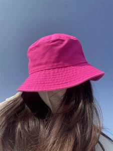 Close-up of rose red cotton bucket hat worn outdoors against a clear blue sky background