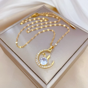 Luxurious gold moon necklace with rabbit ears and clear stones on beige silk background