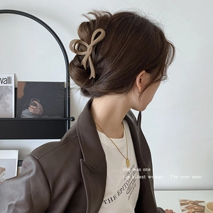 Close-up of a matte brown bow hair claw clip styled on a woman's hair with a leather jacket
