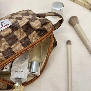 Detailed top view of a corduroy checkered cosmetic bag with skincare items inside