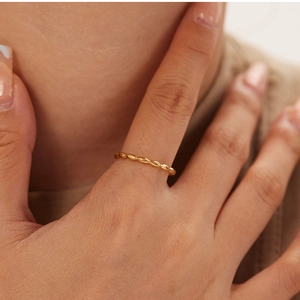 Detail of a thin gold textured rope ring worn on a finger for a chic daily look