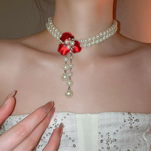Elegant double-layer pearl necklace featuring a red flower pendant with pearl tassels on a model